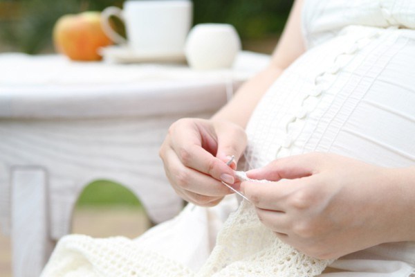 Беременная женщина вяжет крючком